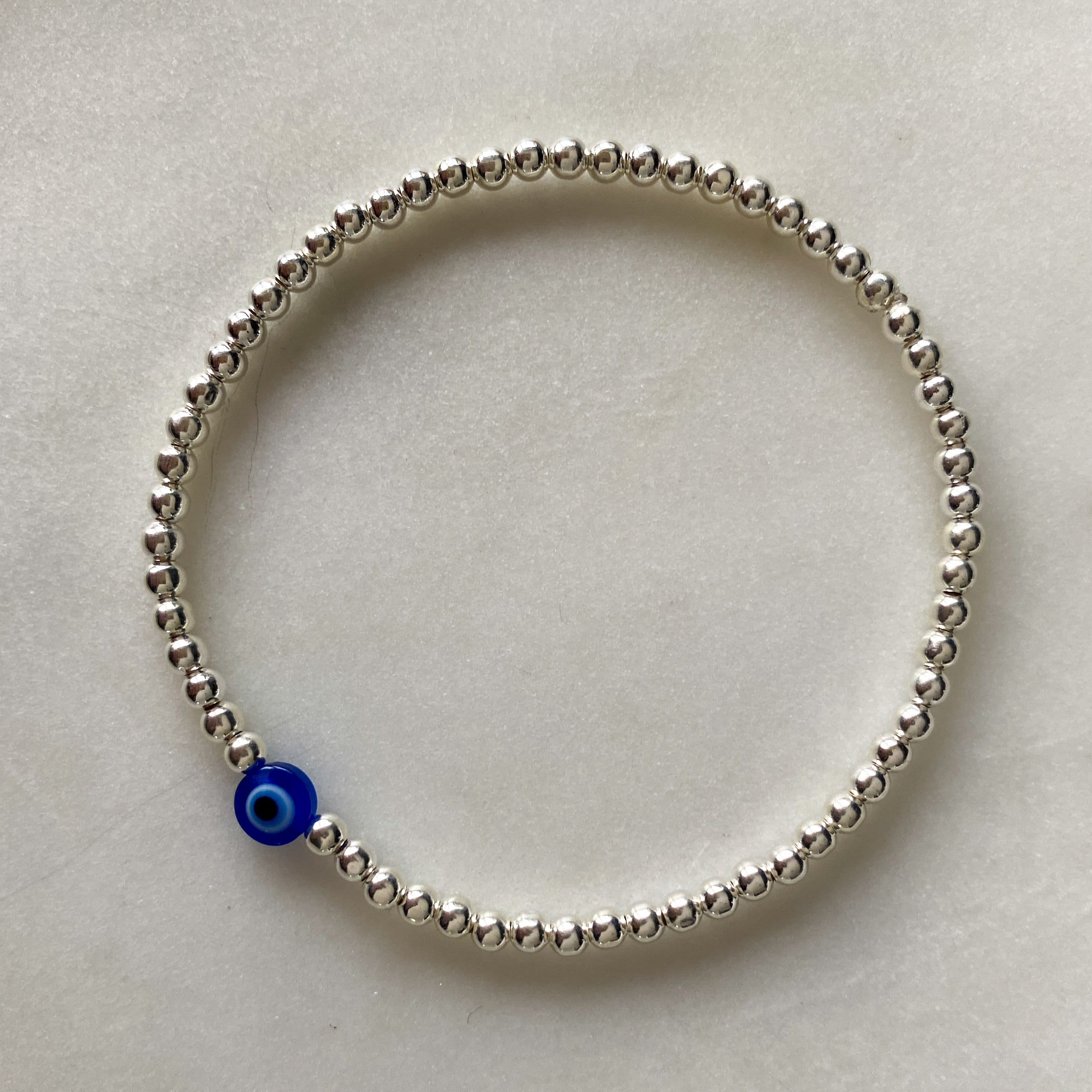 Nazar blue evil eye silver bracelet flat lay – Omasi Collection Finland