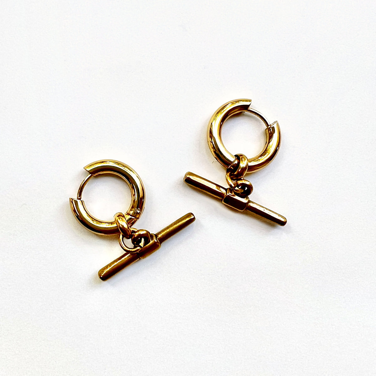 Mova gold tone T-bar hoop earrings in nickel-free surgical steel, flat lay – Omasi Collection