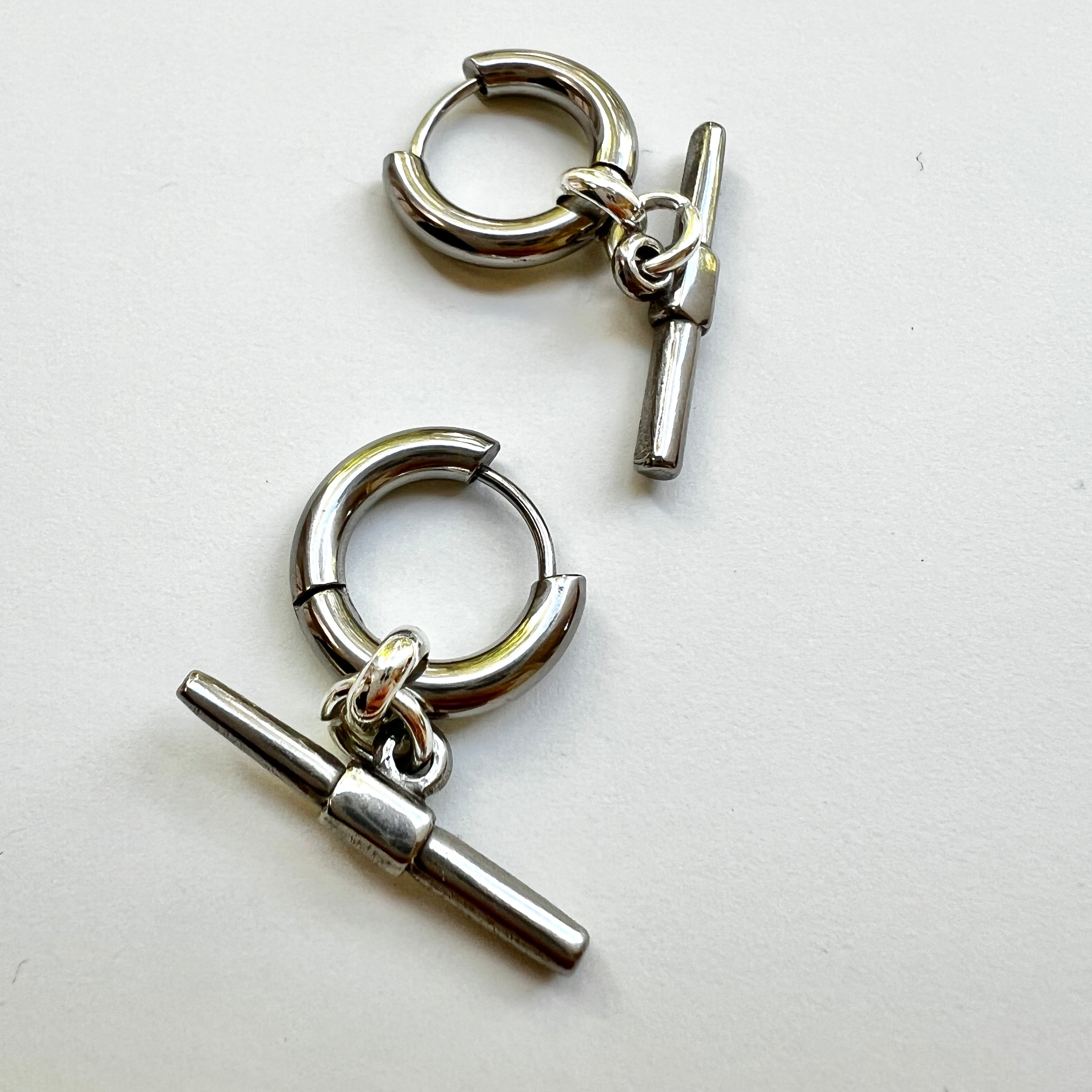Mova gold tone T-bar hoop earrings in nickel-free surgical steel, flat lay – Omasi Collection