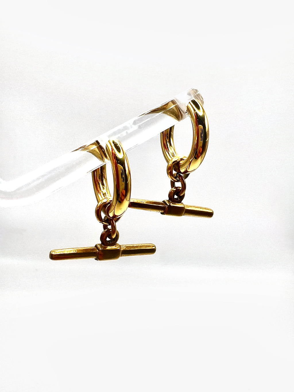 Mova gold tone T-bar hoop earrings hanging on a clear acrylic stand – Omasi Collection