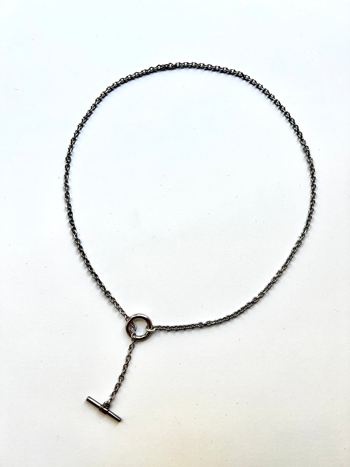 Mova silver tone loop necklace, adjustable T-bar lariat in nickel-free surgical steel, flat lay – Omasi Collection