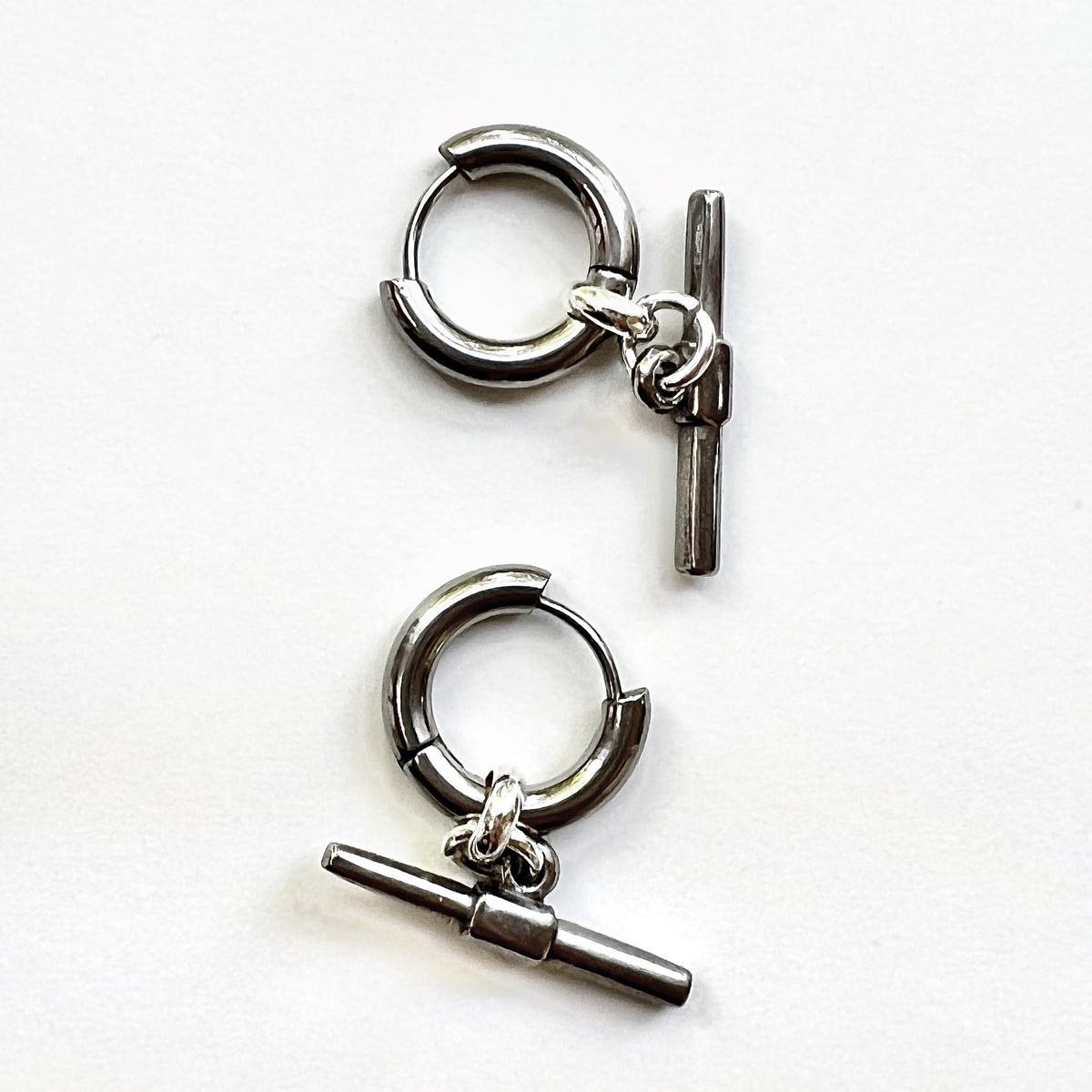 Mova silver tone T-bar hoop earrings in nickel-free surgical steel, flat lay – Omasi Collection