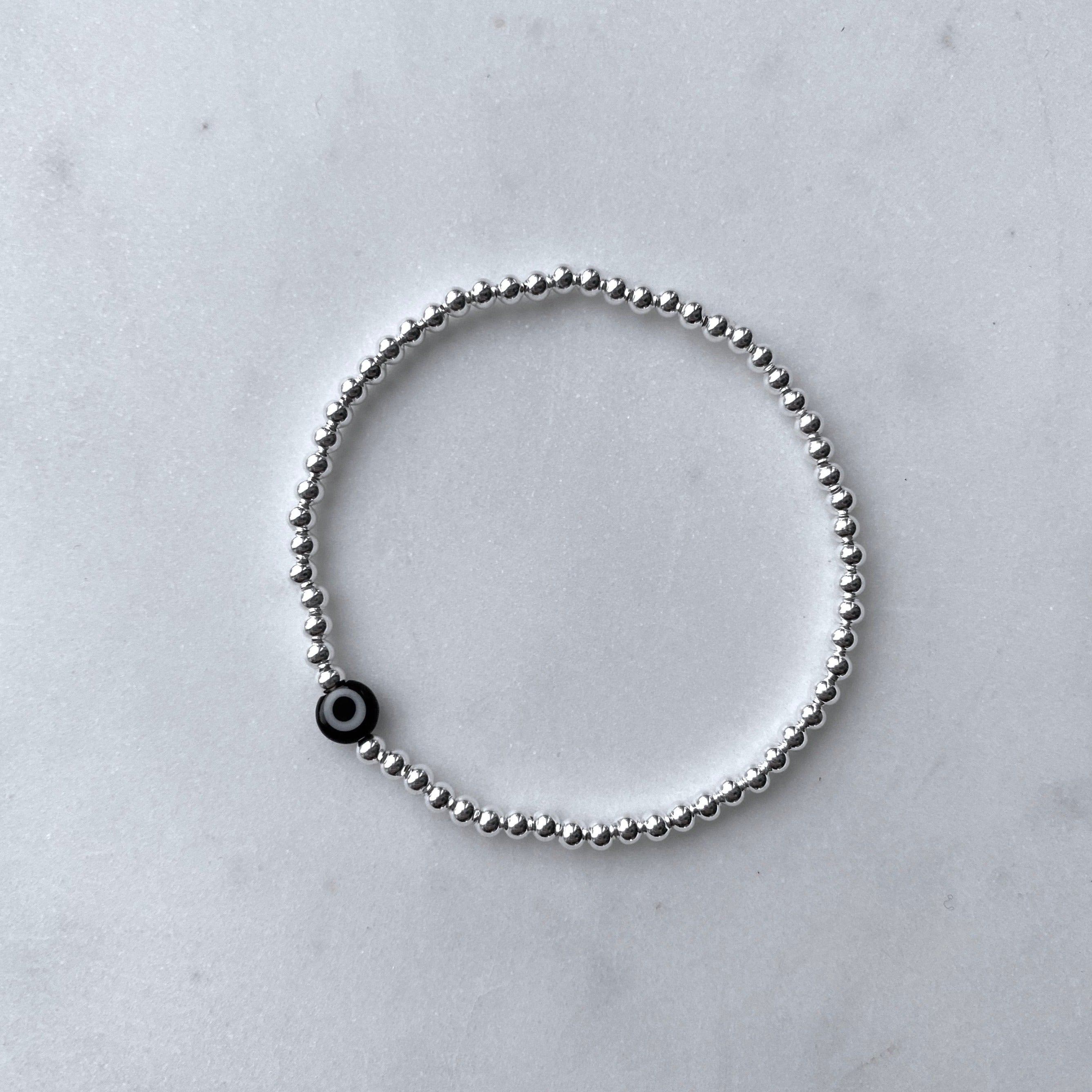 Nazar black evil eye silver bracelet flat lay – Omasi Collection Finland